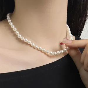 Detail showing high-lustre white pearl necklace worn on neckline as a choker style