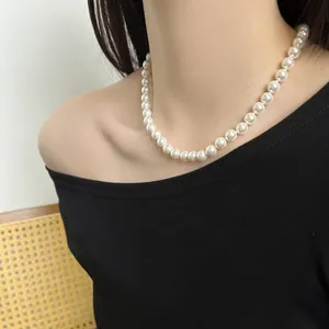 Detail of round white pearl necklace on model with elegant luster and sleek clasp
