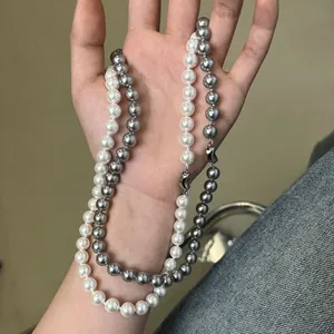 Close-up of white and grey pearl necklaces featuring polished metal lobster clasps