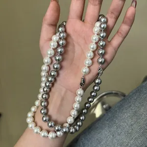 Elegant S925 silver necklace with white and silver-grey pearls held by hand