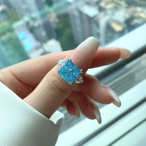 Close-up of radiant cut blue gemstone ring with pear side stones on a hand