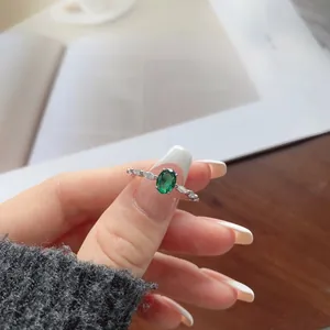 Macro detail of an oval green gemstone ring with marquise zircon accents on silver band