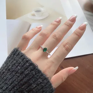 Close-up of S925 silver ring featuring oval green gemstone and zircon on a model's hand