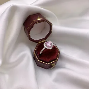 Primer plano de un anillo con gema rosa de corazón y diamantes pavé en estuche de terciopelo