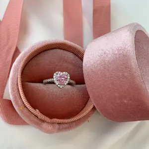 Gros plan d'une bague coeur rose entourée de diamants dans un écrin en velours rose