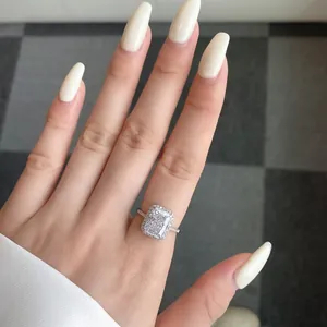 Macro detail of radiant cut S925 silver halo ring with pavé diamonds on woman hand