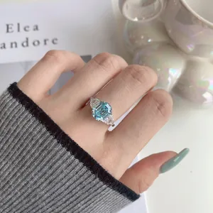 Close-up van een zilveren ring met smaragdgeslepen aquamarijn aan de vinger van een model