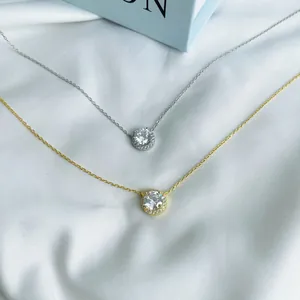 Détail de pendentifs en argent et or avec zircon clair sur tissu satiné blanc