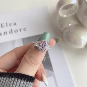 Detailed close-up of emerald-cut pink gemstone ring with triangular side stones