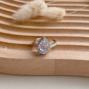 Détail macro d'une bague halo taille poire sur une surface en bois texturé