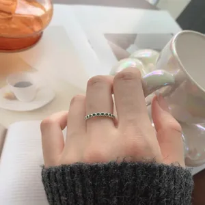 Detailed view of an S925 silver ring with small green zircons worn on the finger