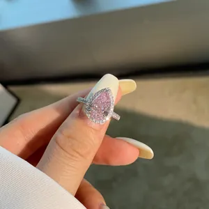 Détail macro d'une bague diamant rose en forme de poire avec halo et anneau argent