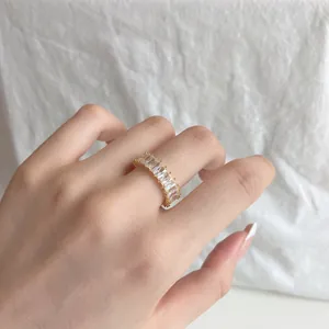 Close-up of gold ring with baguette-cut clear zircons on model's finger
