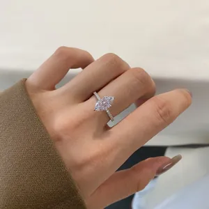 Close-up of a marquise cut diamond ring with pavé set band worn on a hand