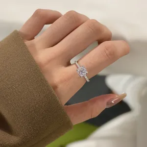 Macro detail of cushion cut solitaire engagement ring with pavé diamond band on finger