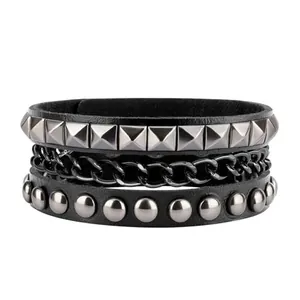 Detail showing multilayer black leather bracelet with punk pyramid studs and metal chain
