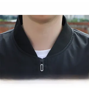 Detail of a minimalist black men's baseball jacket featuring a contrast zipper neckline
