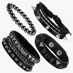 Close-up of four black punk bracelets with silver metal spikes, studs, and chain details