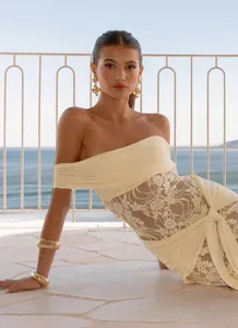 Detail view of the lace floral pattern and pleated waist on a beige off-shoulder dress