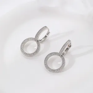 Macro view of silver circle hoop earrings with zircon stones on white ceramic tray
