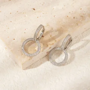 Macro detail of silver hoop earrings with pavé-set zircons on natural stone base