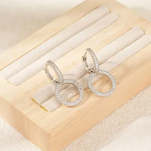 Macro detail of silver huggie earrings with pave-set zirconias on wooden jewelry box
