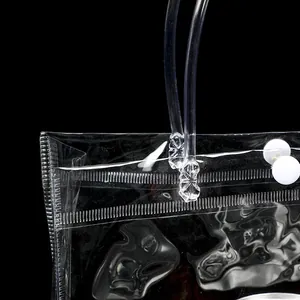 Detail of transparent PVC gift bag with snap button closure and reinforced handle joints