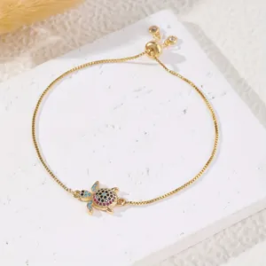 Detail of a gold turtle bracelet with multi-color zircon stones and adjustable box chain