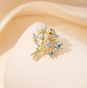 Close-up of golden flower brooch with pearls and sparkling rhinestones on fabric