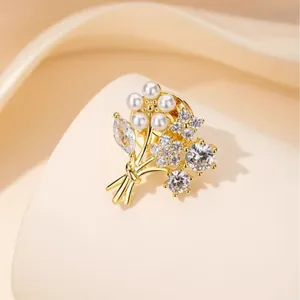 Elegant gold flower brooch featuring white pearls and zircon crystals on a satin background