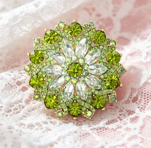 Macro shot of luxury green crystal sunflower brooch with gold metal base on lace