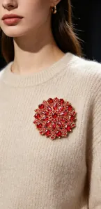 Detail view of a luxury red crystal sunflower brooch pinned on a beige sweater