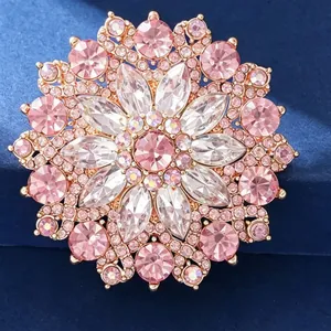 Elegant sun flower brooch with pink crystals and rose gold plating on dark blue fabric