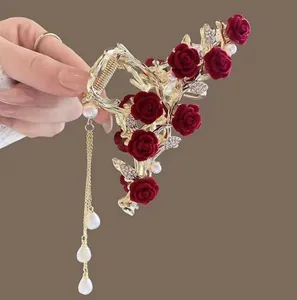 Detailed view of golden hair claw with red velvet roses and pearl tassel chains