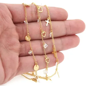 Macro view of 18K gold plated chain with heart, cross, and crystal charms in hand