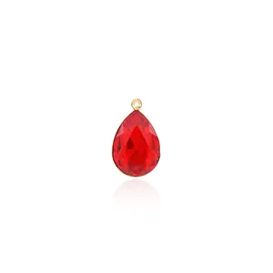 Macro detail of a 18K gold-plated teardrop pendant with red zircon and faceted crystal surface