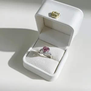 Detailed view of heart-shaped pink gemstone ring in a crown-branded jewelry box