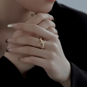 Nahaufnahme eines doppellagigen goldenen X-förmigen Kreuzrings mit glitzernden Zirkonsteinen