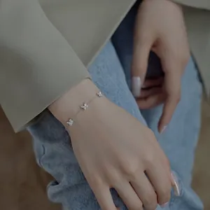 Gros plan d'un bracelet en argent S925 avec trois breloques papillon au poignet
