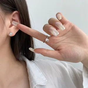 Model wearing square-cut zircon stud earrings and a matching silver solitaire ring