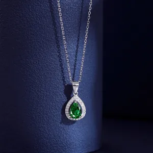 Détail macro du pendentif en zircon émeraude poire avec chaîne en argent sur bleu