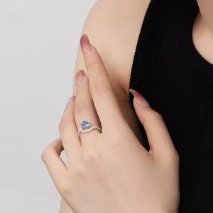 Detalle macro de anillo con piedra preciosa azul lágrima y pavé de diamantes en plata