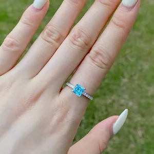 Makroaufnahme von Aquamarinring mit quadratischem Schliff an einer Hand