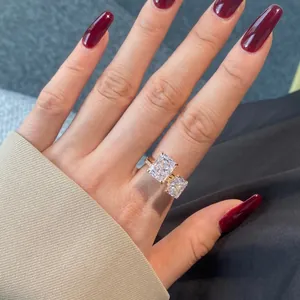 Close-up of Toi et Moi gold ring with radiant cut stones worn on a female finger