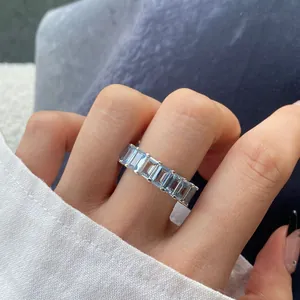 Nahaufnahme von Aquamarin-Steinen im Smaragdschliff in einem Eternity-Ring am Finger