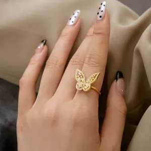 Detailed view of a gold butterfly ring with zircon pavé setting on a model's hand