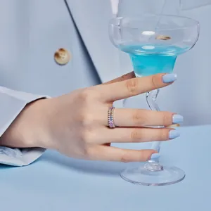 Close-up of rainbow baguette-cut zircon ring worn by a model holding a glass