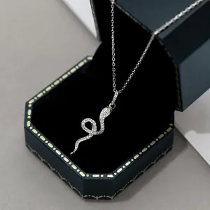 Gros plan détaillé d'un pendentif serpent en argent avec des yeux en gemmes vertes sur écrin