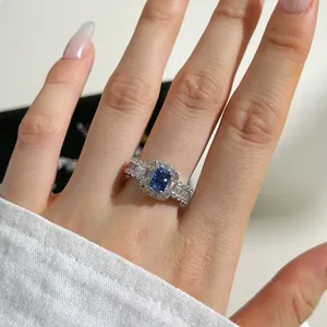 Macro shot of an emerald-cut blue gemstone ring with pave diamonds on a silver band