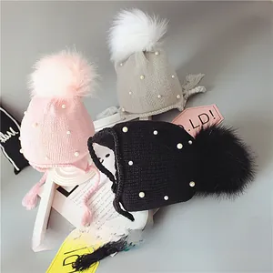 Détails de bonnets en tricot avec pompon, perles et cache-oreilles en rose, gris et noir